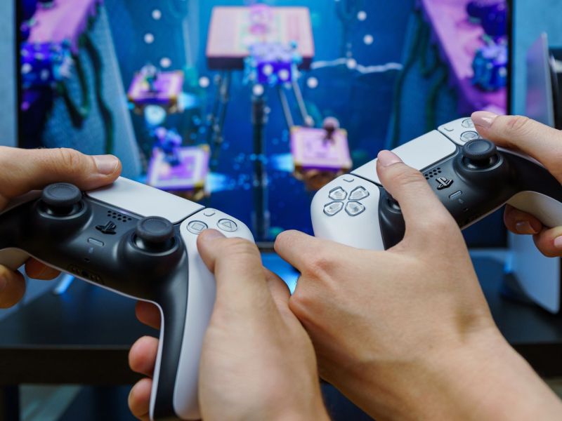 Zwei Personen halten PS5-Controller in der Hand und spielen.