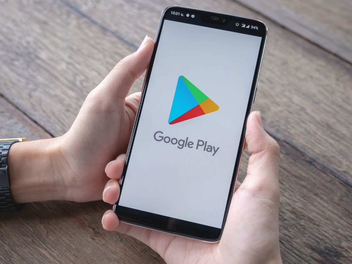 Person hält ein Handy mit dem Loge des Google Play Store in den Händen.