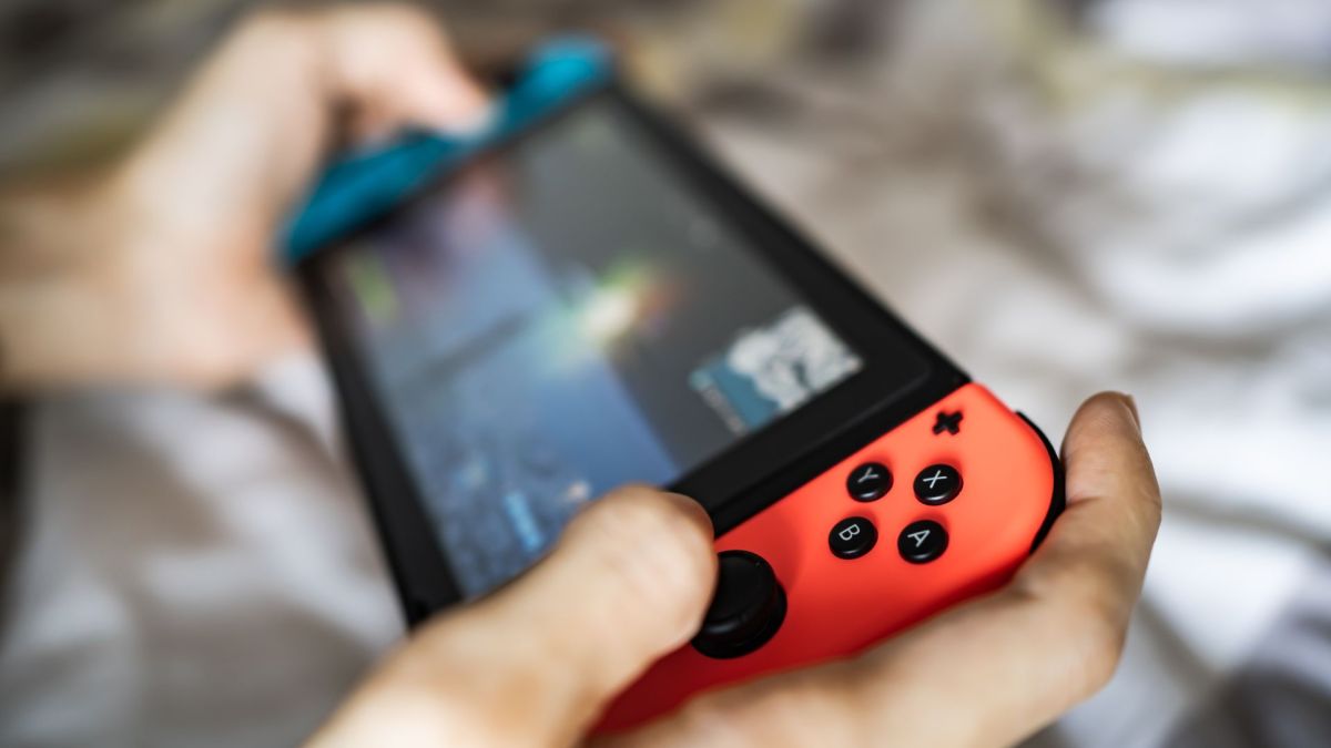 Eine Person hält die Nintendo Switch in den Händen und spielt damit.