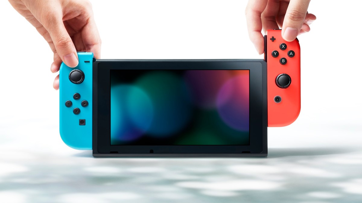 Eine Nintendo Switch mit einem roten und blauen Joy-Con und zwei Händen.