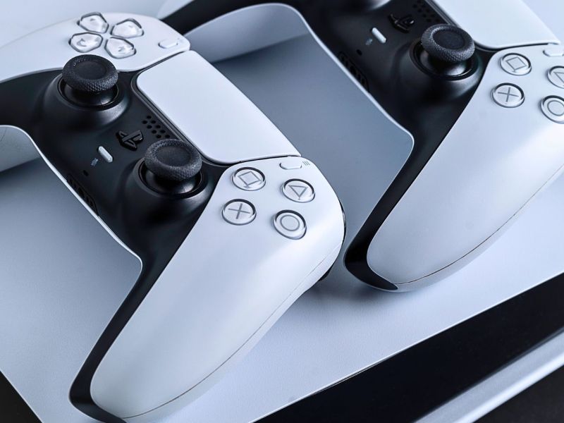 Zwei PS5-Controller liegen auf einer PlayStation.