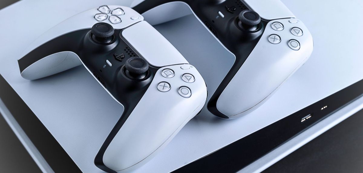 Zwei PS5-Controller liegen auf einer PlayStation.